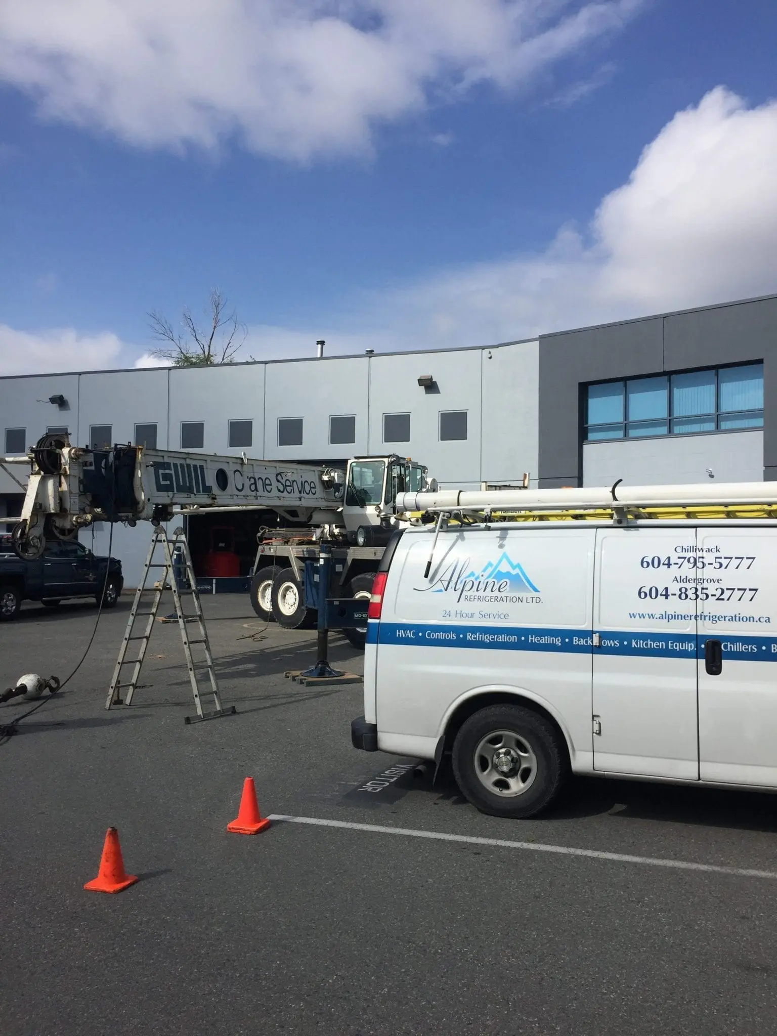 Commercial HVAC Installation with Crane Service Alpine Refrigeration van with crane service at commercial HVAC installation site